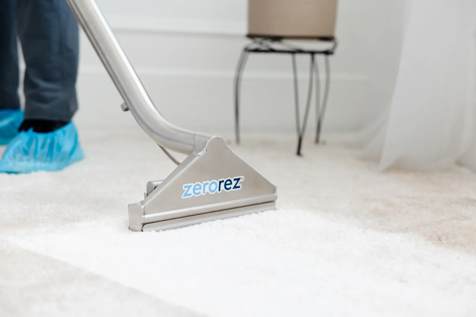 Zerorez&reg; Zr&reg; Wand being used by a technician with blue booties on to clean a white carpet