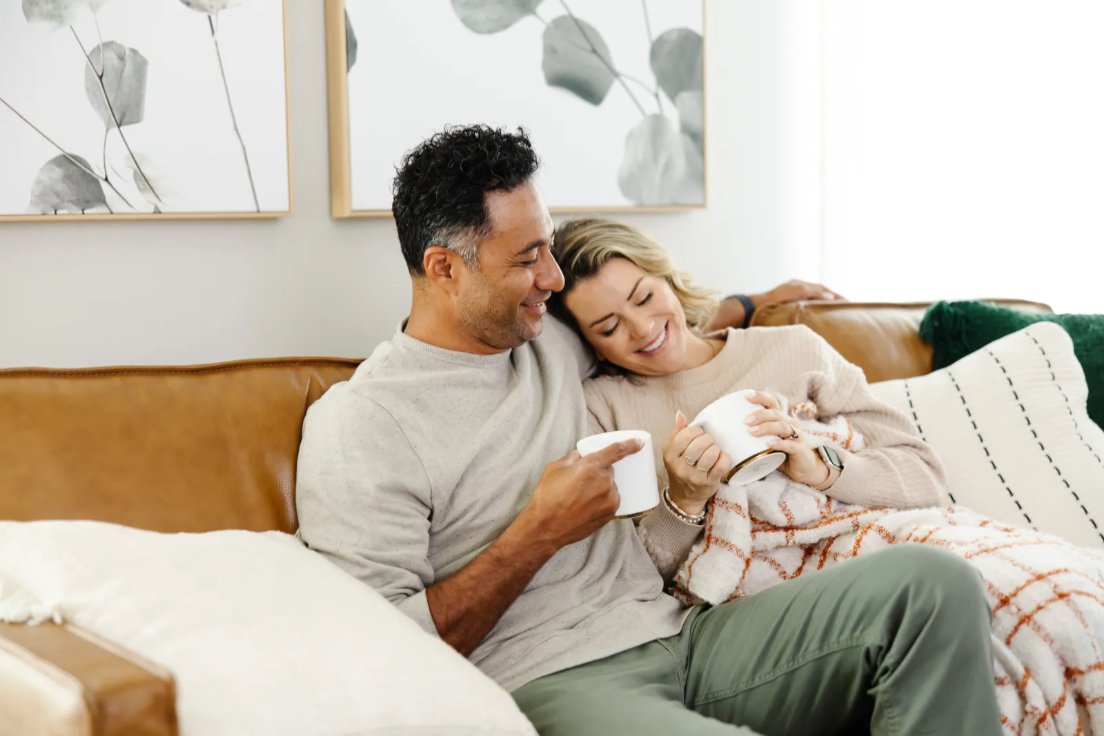 man and woman on a couch snuggling with a blanket